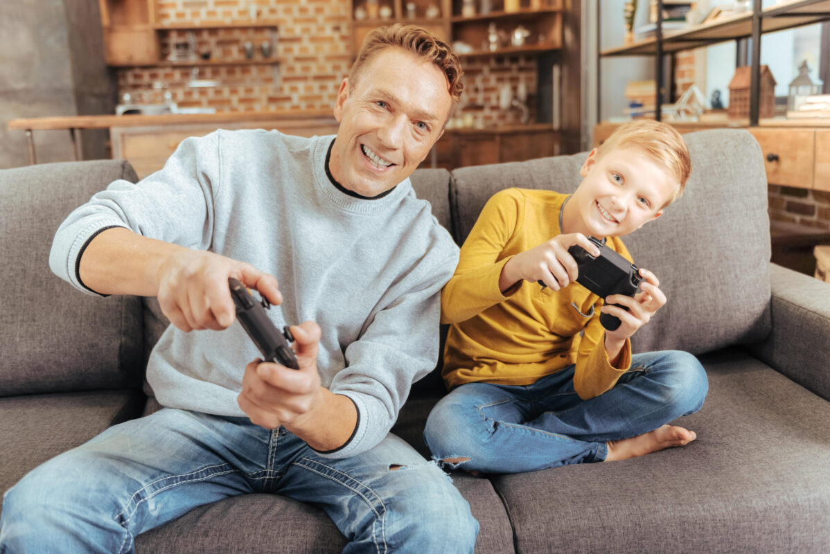 Happy delighted father and son playing video games
