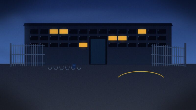 Cool blue hour photo of empty secondary school gates at dusk, with bike racks, one bicycle and a lone backpack on the tarmac